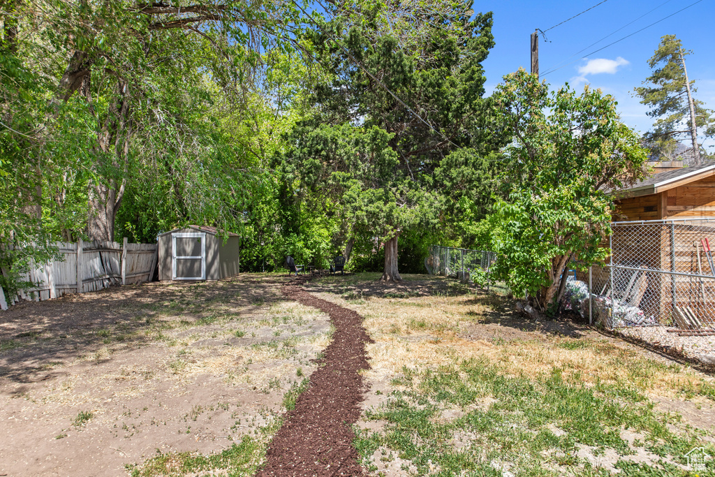 Fenced backyard featuring a shed and an outdoor structure