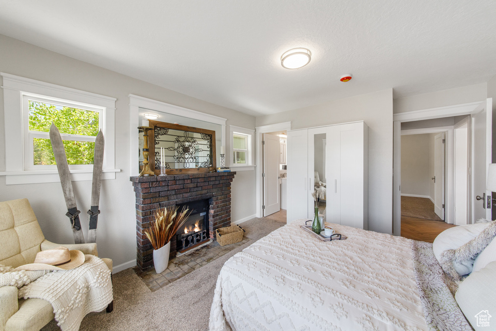 Carpeted bedroom with a fireplace and baseboards
