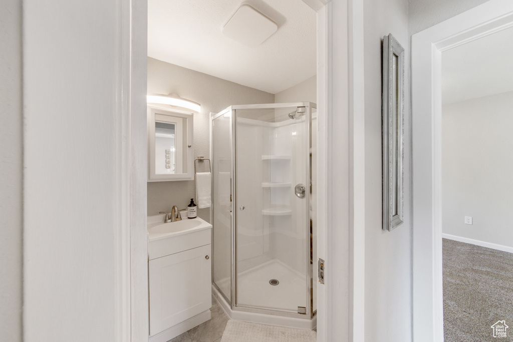 Full bathroom featuring a stall shower, vanity, and baseboards