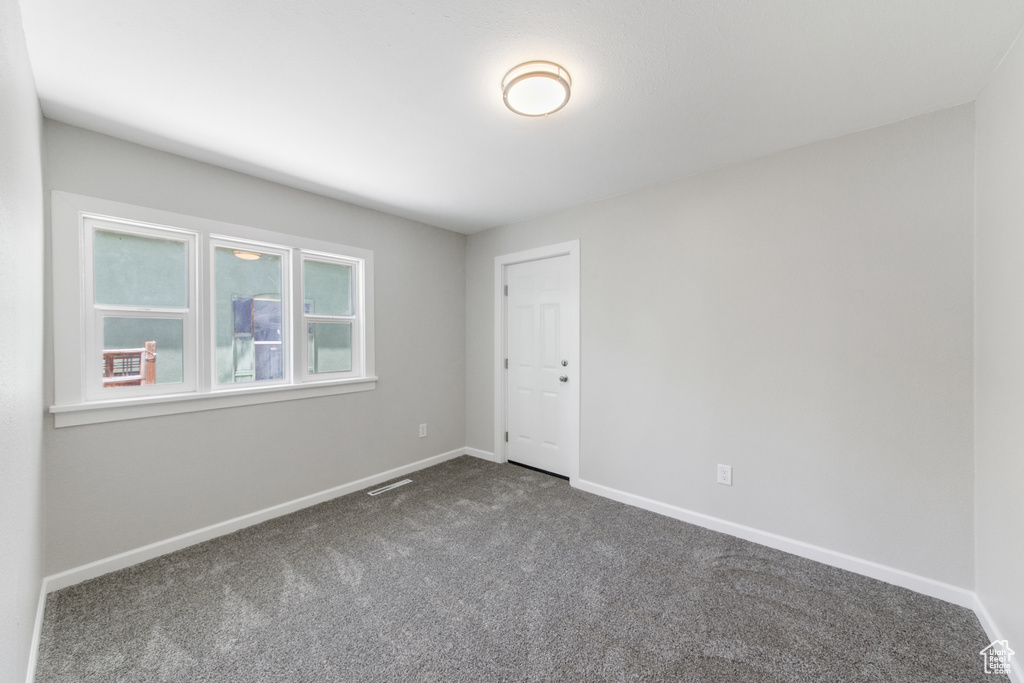 Unfurnished room with dark carpet and baseboards