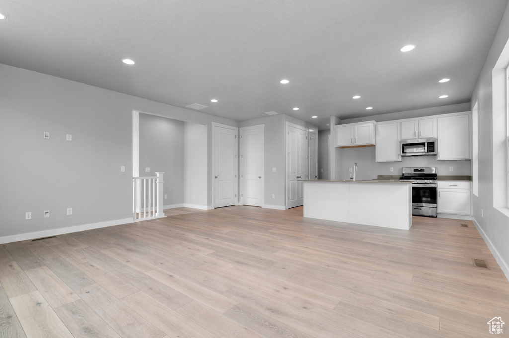 Kitchen featuring stainless steel appliances, a sink, recessed lighting, white cabinets, and open floor plan