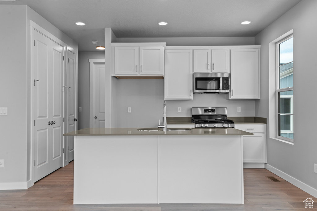 Kitchen featuring appliances with stainless steel finishes, a sink, white cabinetry, recessed lighting, and baseboards