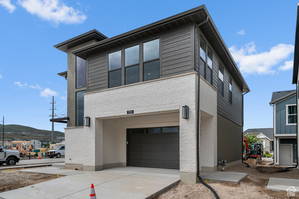 View of property exterior with an attached garage, concrete driveway, and brick siding
