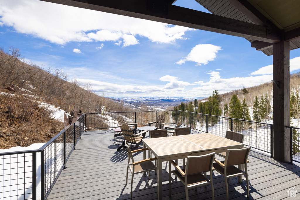 Snow covered deck featuring a mountain view and outdoor dining area
