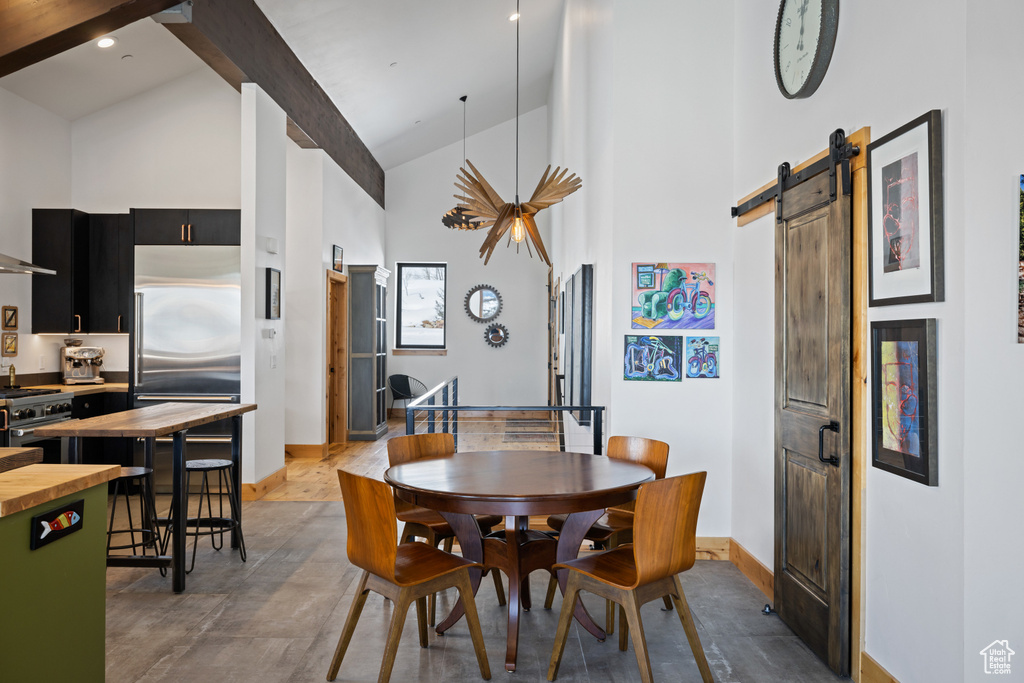 Dining space with high vaulted ceiling, baseboards, a barn door, and beamed ceiling