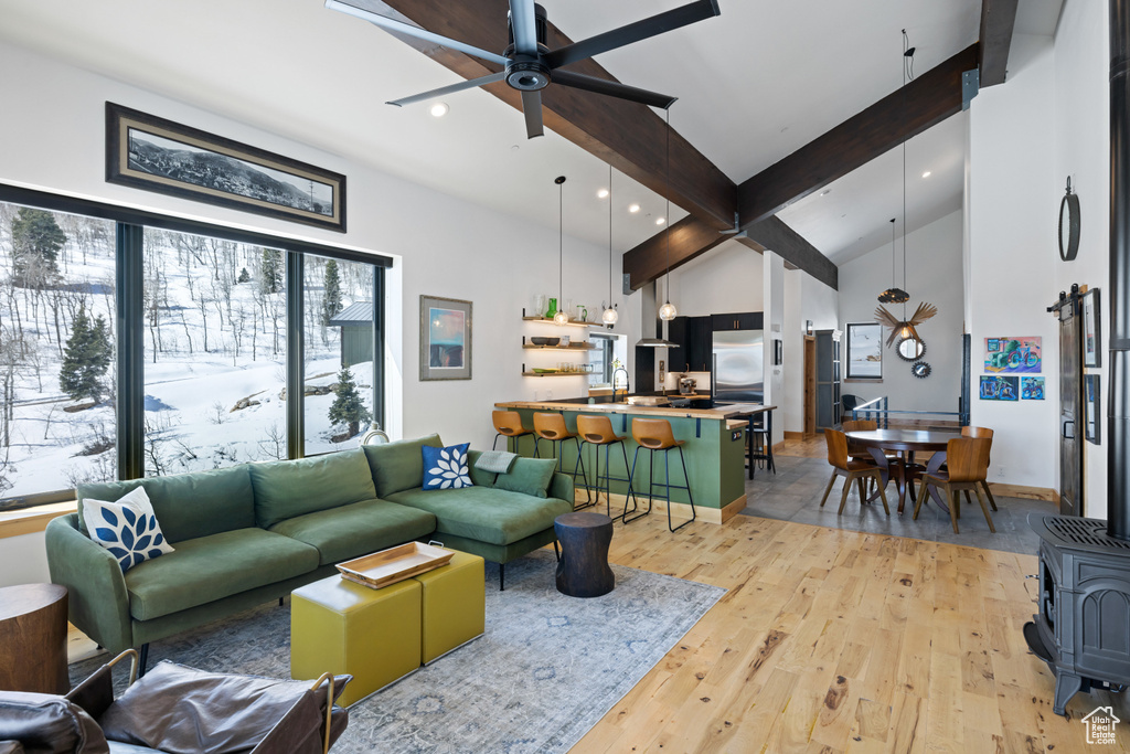 Living room featuring ceiling fan, light wood-style flooring, recessed lighting, a wood stove, and high vaulted ceiling