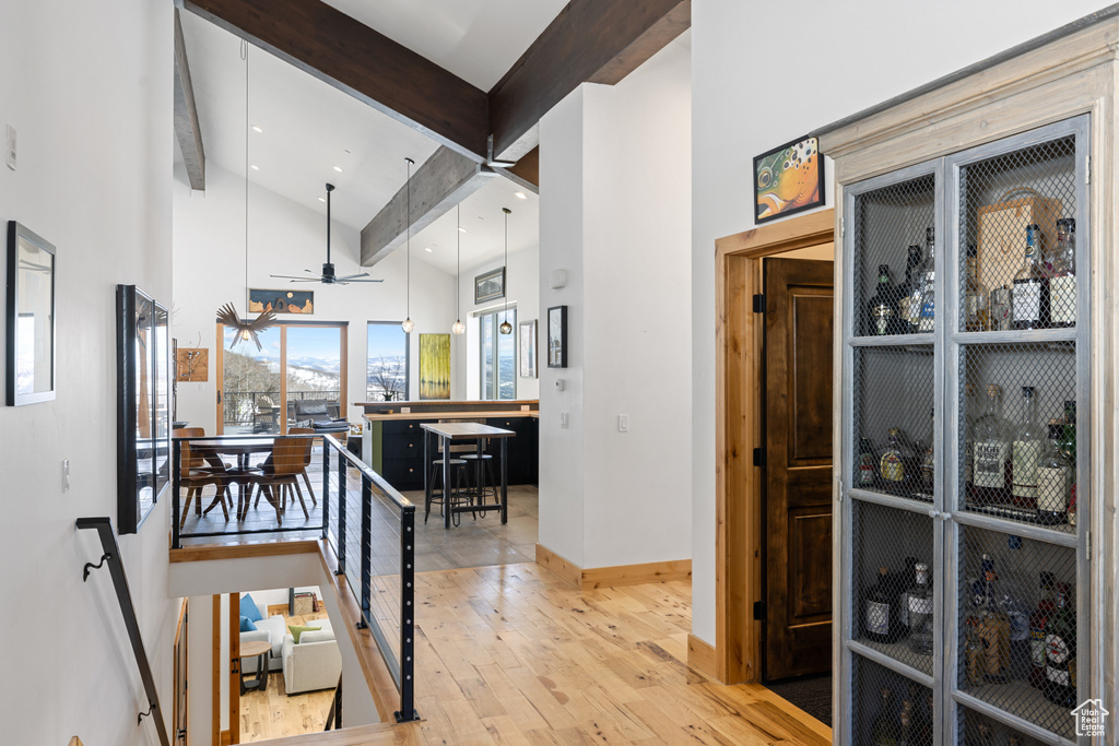 Corridor with baseboards, wood finished floors, high vaulted ceiling, and recessed lighting