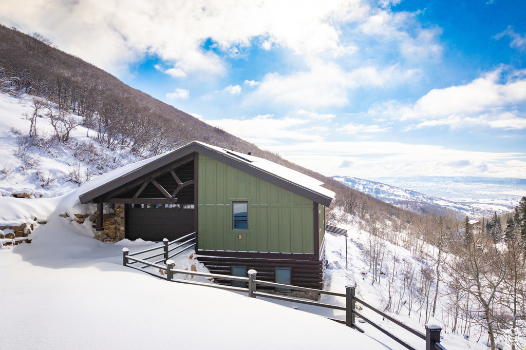 View of snow covered exterior with board and batten siding and a mountain view