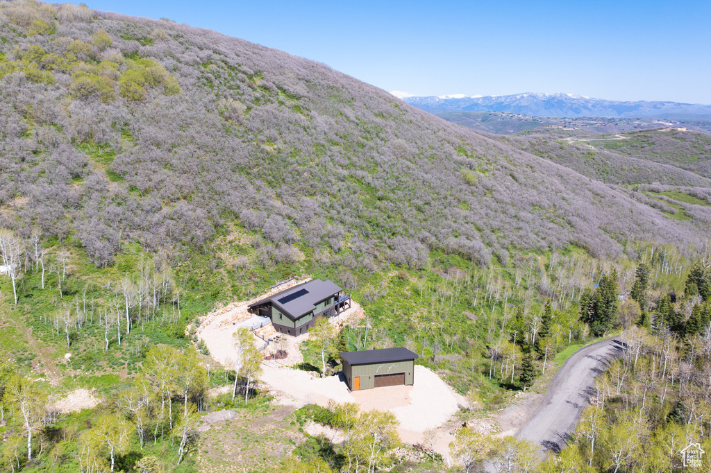 Aerial view of property and surrounding area with mountains and a heavily wooded area