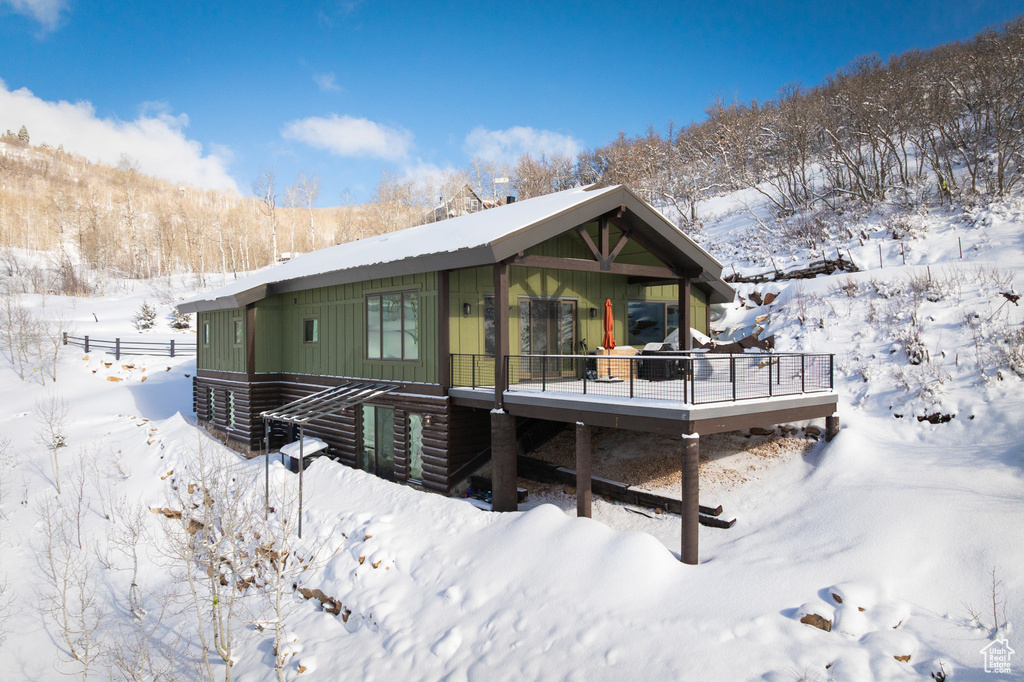 Snow covered rear of property featuring a deck