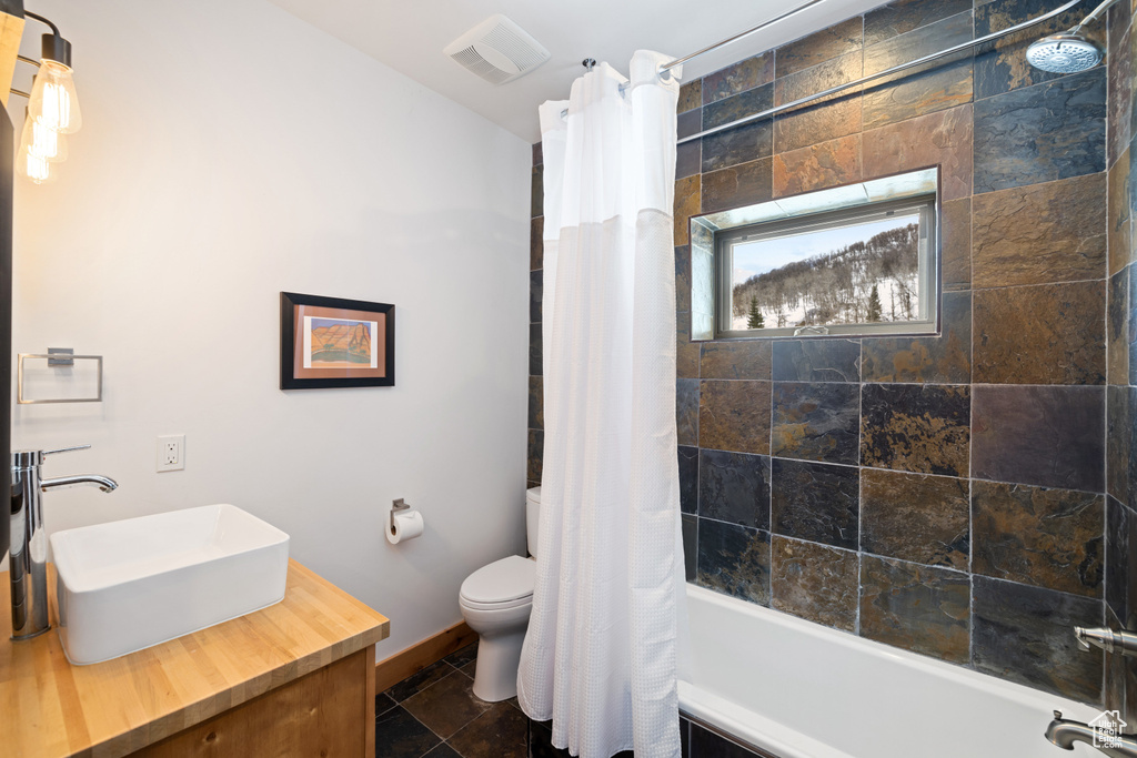 Bathroom featuring shower / bathtub combination with curtain, toilet, baseboards, and vanity