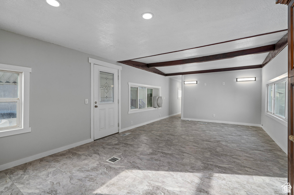 Spare room with beam ceiling, baseboards, a textured ceiling, and recessed lighting