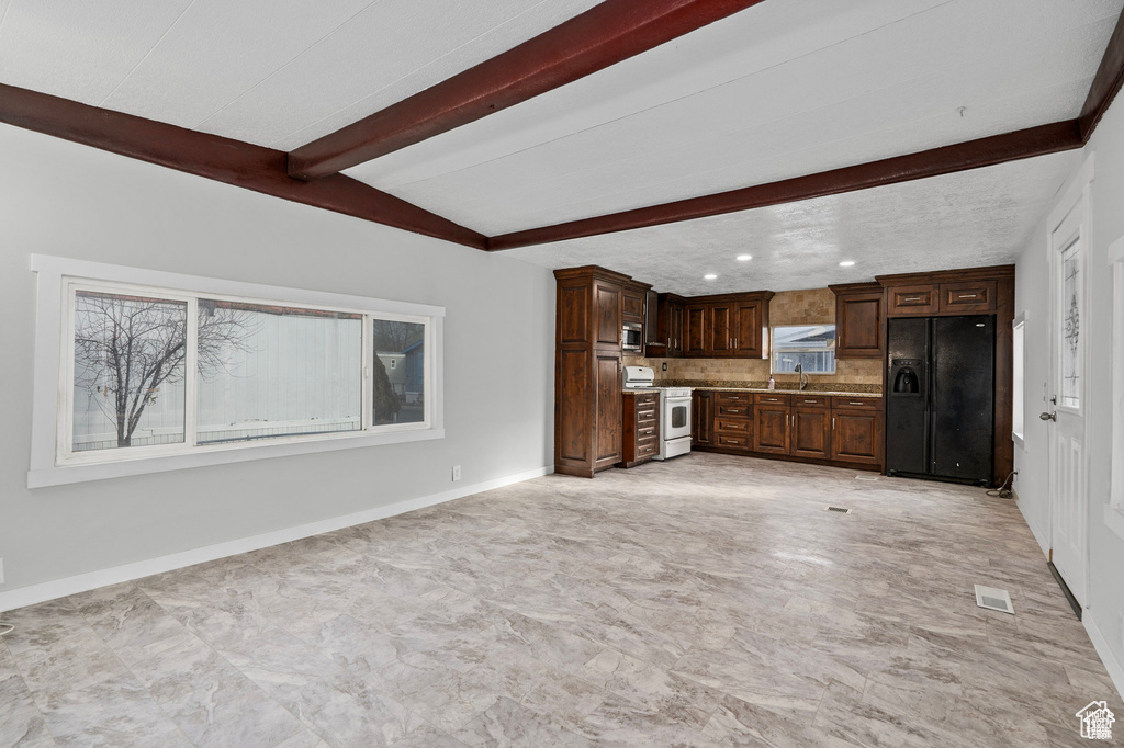 Unfurnished living room featuring beamed ceiling, a sink, baseboards, and recessed lighting