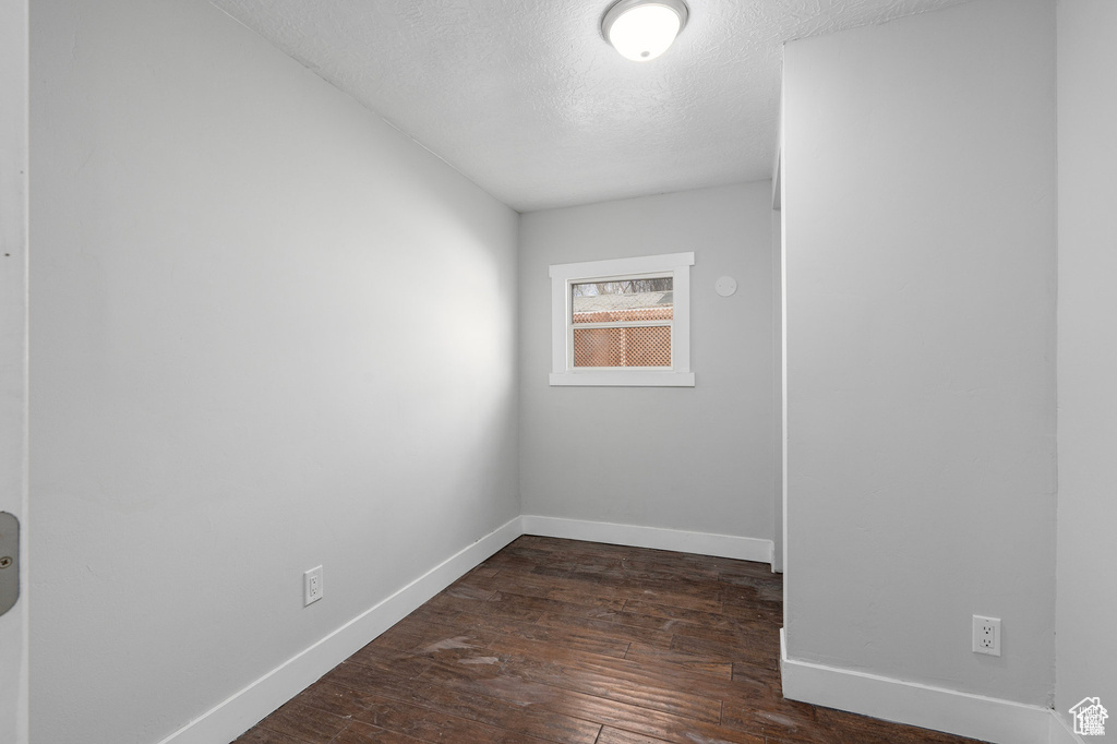 Spare room with baseboards, dark wood-style flooring, and a textured ceiling