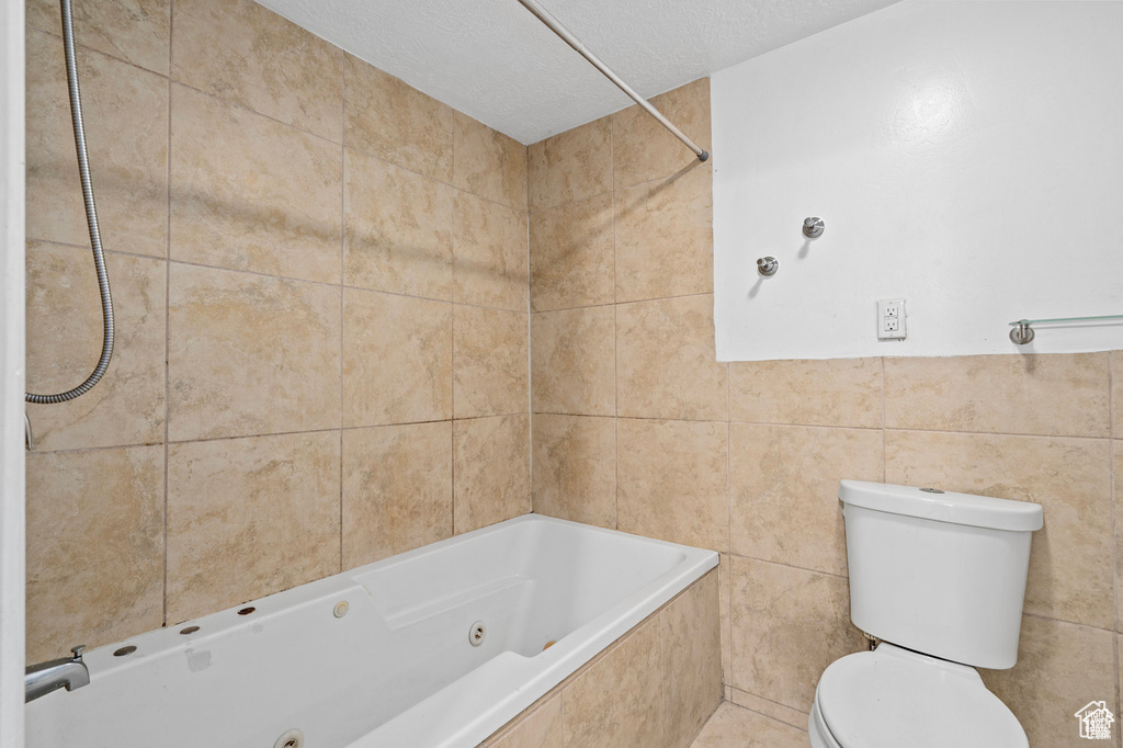 Bathroom featuring toilet and tile walls