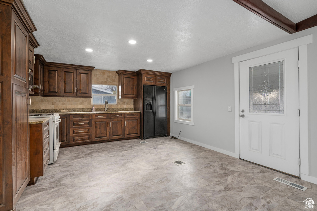Kitchen with black fridge, white range with gas cooktop, light countertops, tasteful backsplash, and recessed lighting