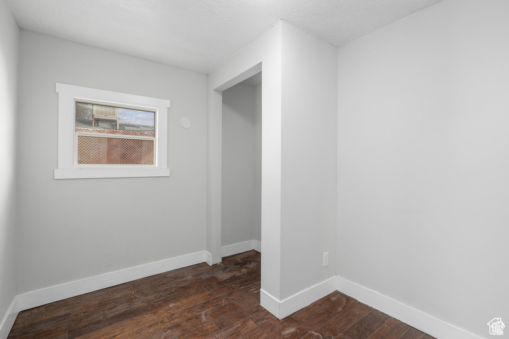 Spare room featuring dark wood-type flooring and baseboards