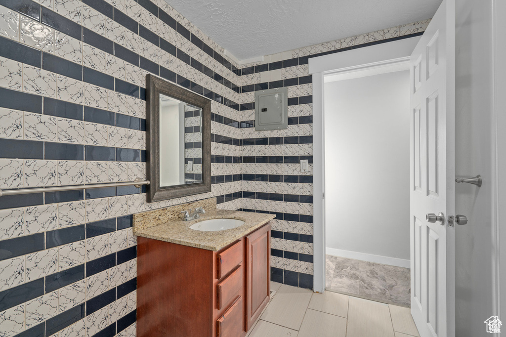 Bathroom with electric panel, vanity, a textured ceiling, and tile patterned flooring