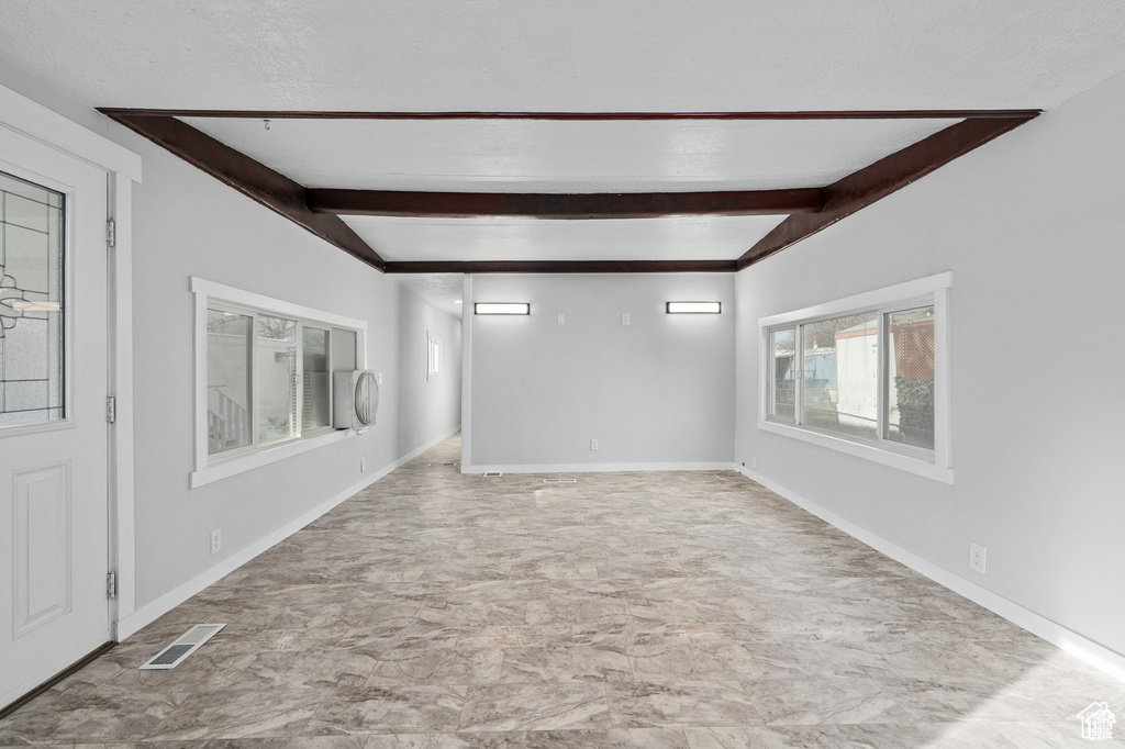 Spare room featuring beam ceiling and baseboards