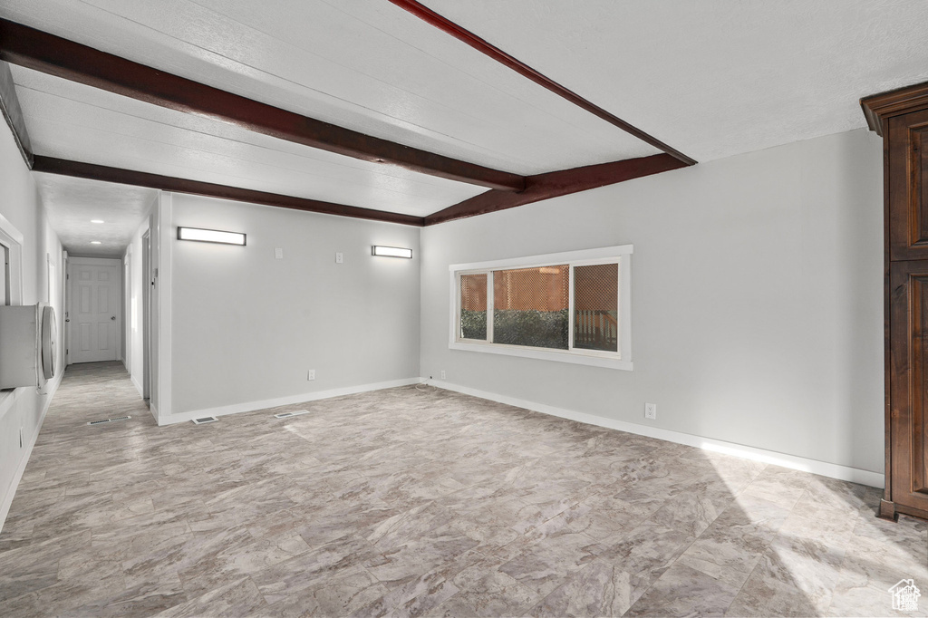 Empty room with beamed ceiling and baseboards