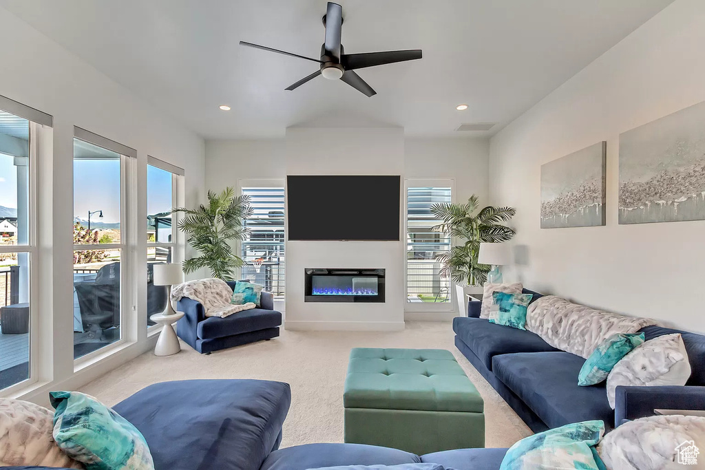Carpeted living area with ceiling fan, a glass covered fireplace, and recessed lighting