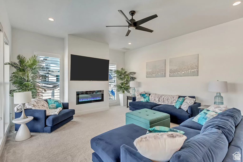 Living room featuring carpet floors, healthy amount of natural light, recessed lighting, a ceiling fan, and a glass covered fireplace