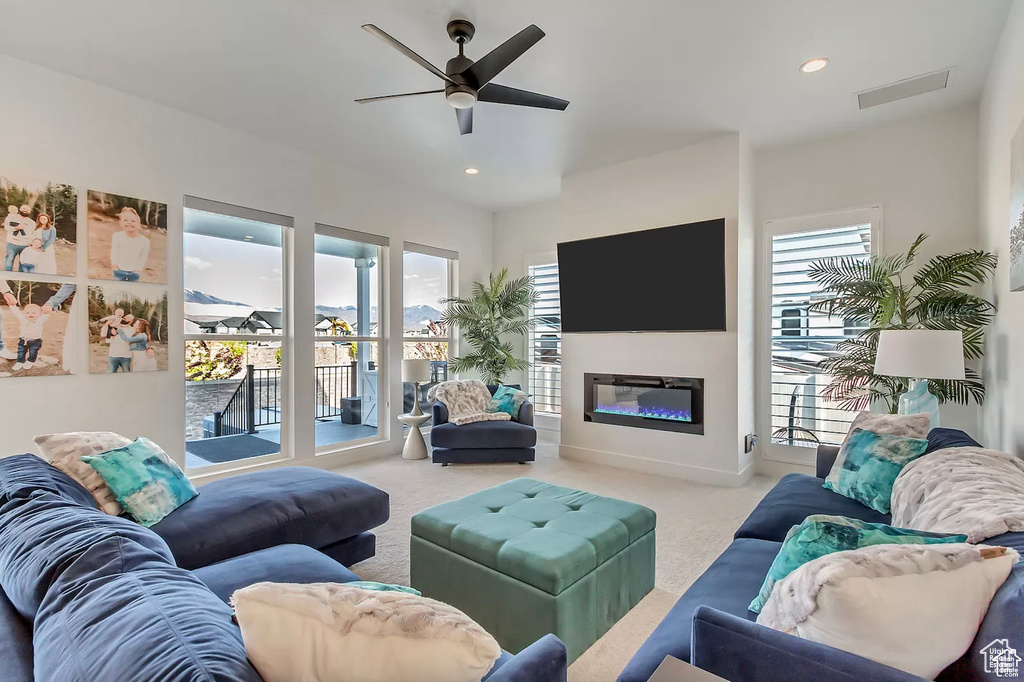 Carpeted living room with a ceiling fan, healthy amount of natural light, a glass covered fireplace, recessed lighting, and baseboards