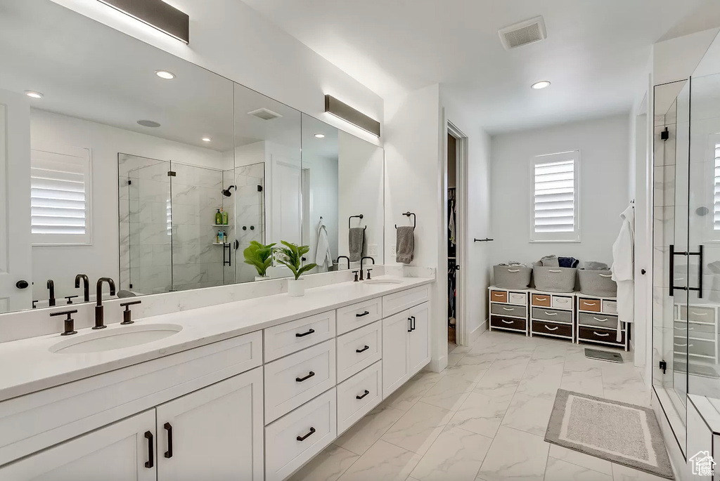Bathroom with a shower stall, recessed lighting, double vanity, and marble finish flooring