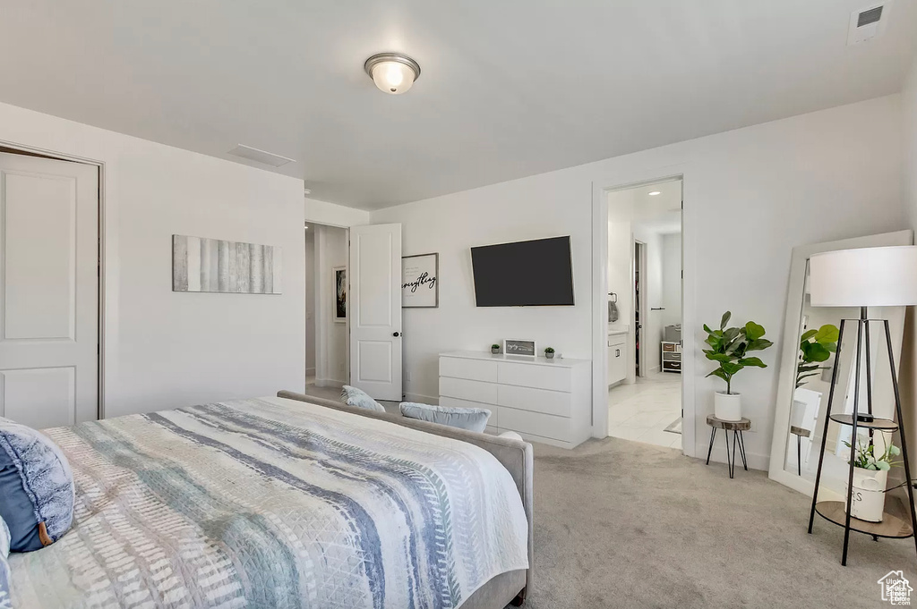 Bedroom with light colored carpet and connected bathroom