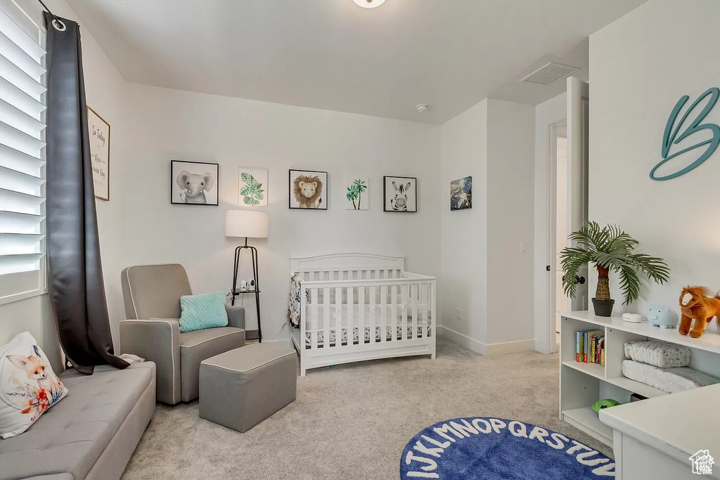 Bedroom featuring carpet floors, a crib, and baseboards