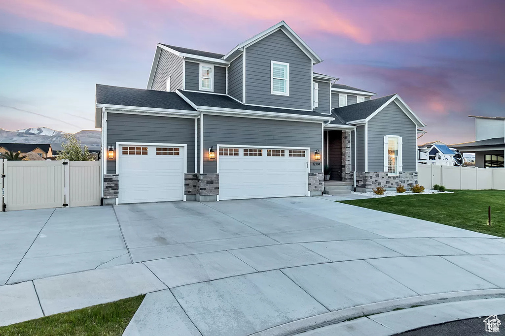 View of front facade featuring concrete driveway, an attached garage, a garage, a gate, and stone siding