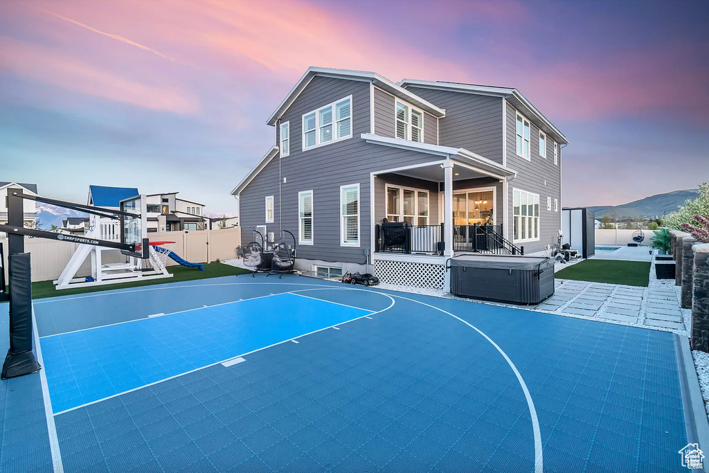 View of basketball court featuring a playground, a fenced backyard, and basketball hoop