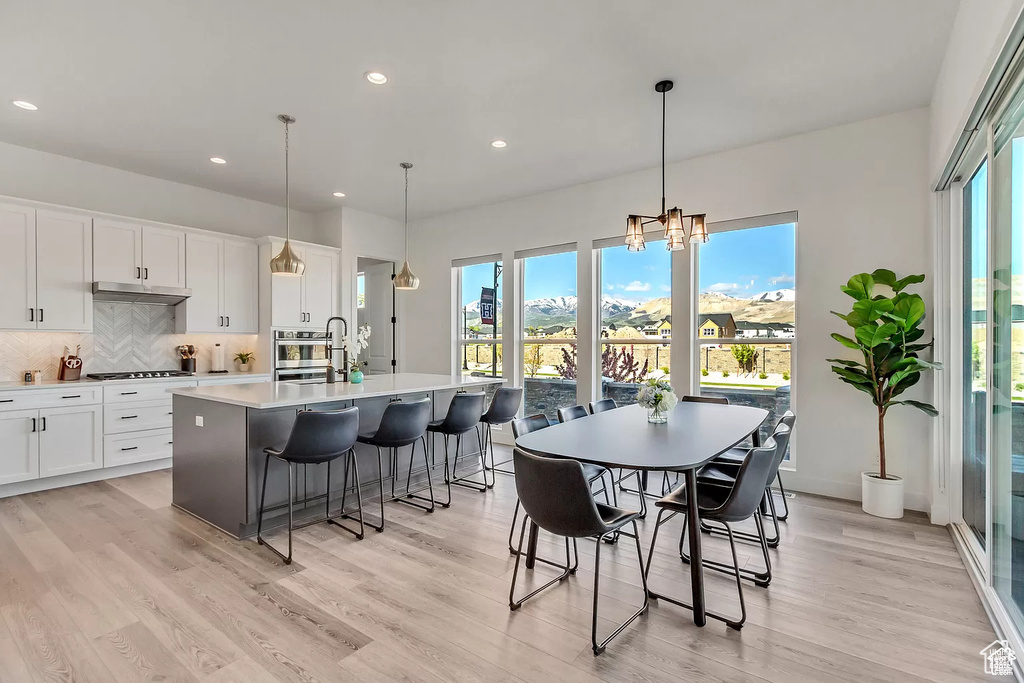 Dining space featuring healthy amount of natural light, light wood-type flooring, recessed lighting, a chandelier, and baseboards