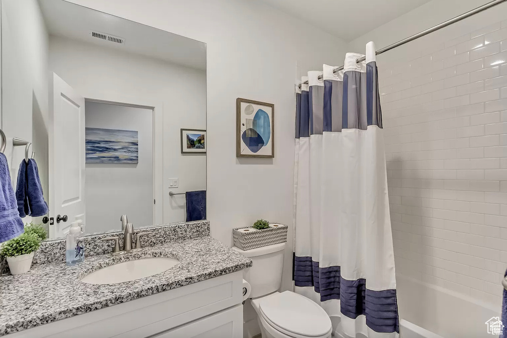 Bathroom with vanity, toilet, and shower / tub combo with curtain