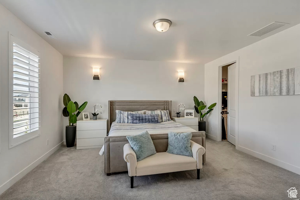 Bedroom featuring light carpet, multiple windows, and baseboards