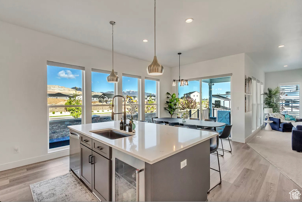 Kitchen with a sink, beverage cooler, baseboards, light wood-style floors, and recessed lighting