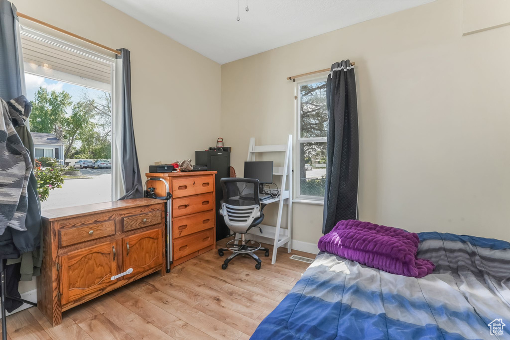 Bedroom with light wood finished floors and an office area