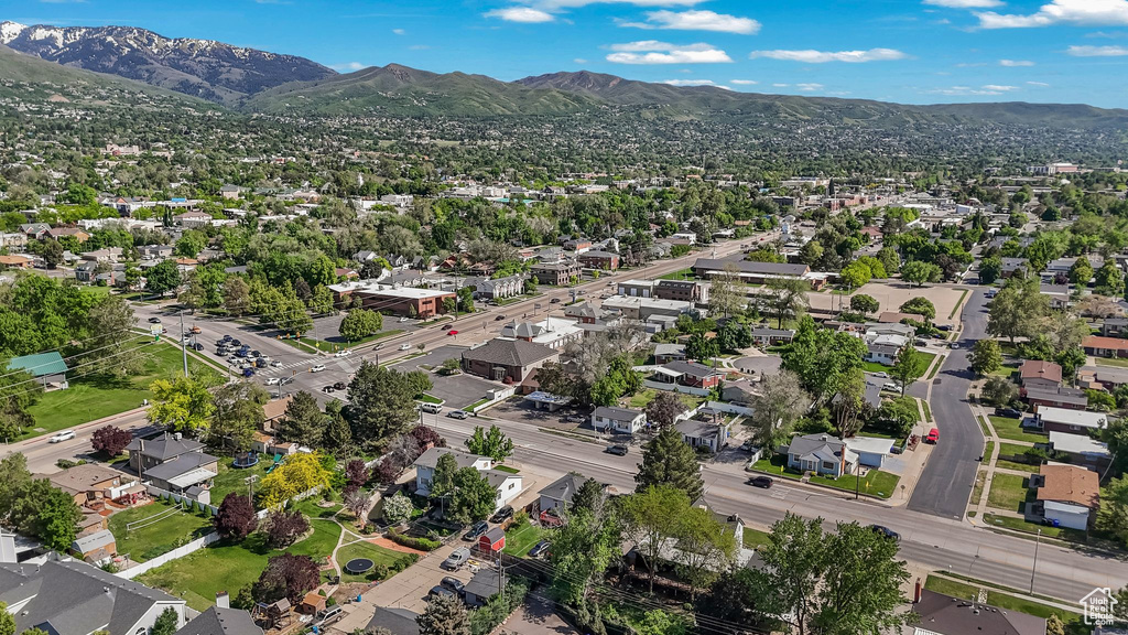Aerial view of property and surrounding area featuring a mountainous background and nearby suburban area