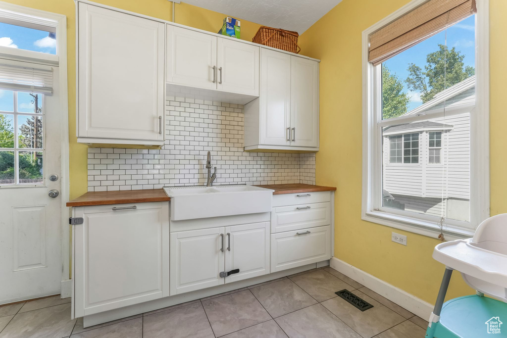 Kitchen with butcher block counters, a sink, decorative backsplash, and healthy amount of natural light