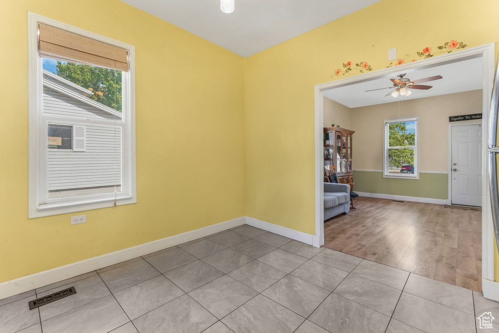 Tiled spare room featuring a ceiling fan and baseboards