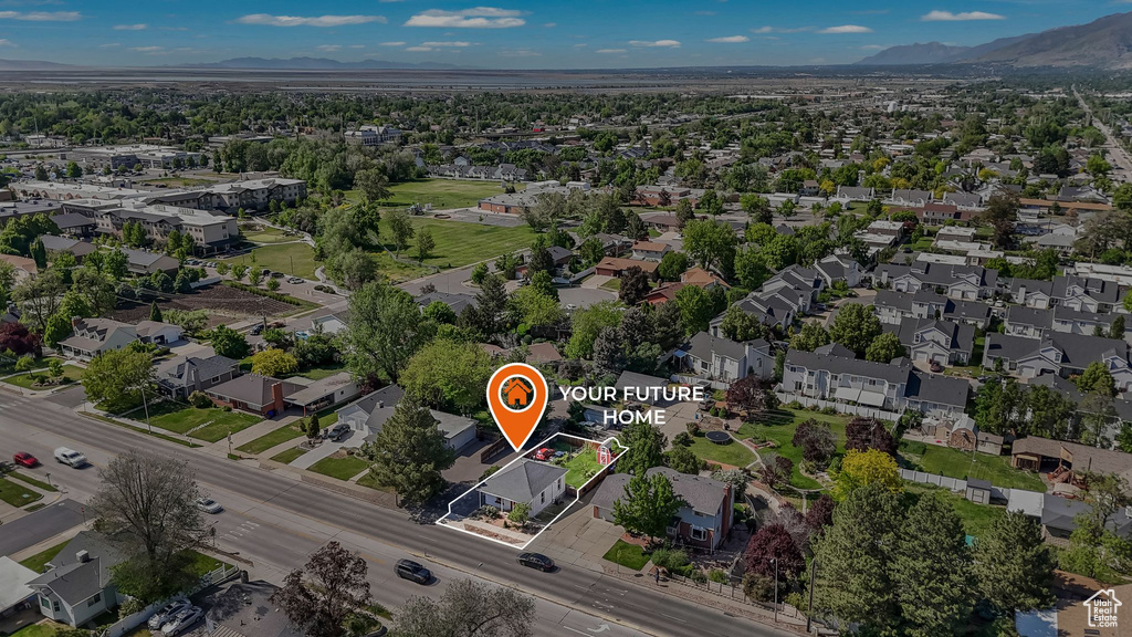 Aerial view of property and surrounding area featuring mountains, property parcel outlined, and nearby suburban area