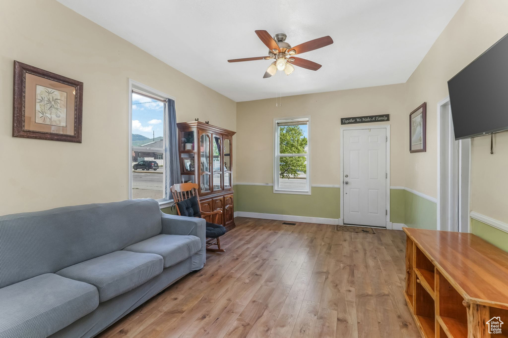 Living area with light wood-type flooring, ceiling fan, and baseboards