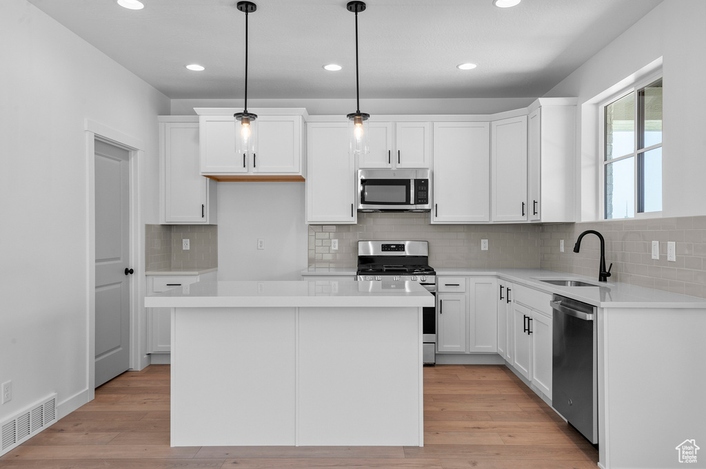 Kitchen featuring stainless steel appliances, a sink, white cabinets, recessed lighting, and light countertops