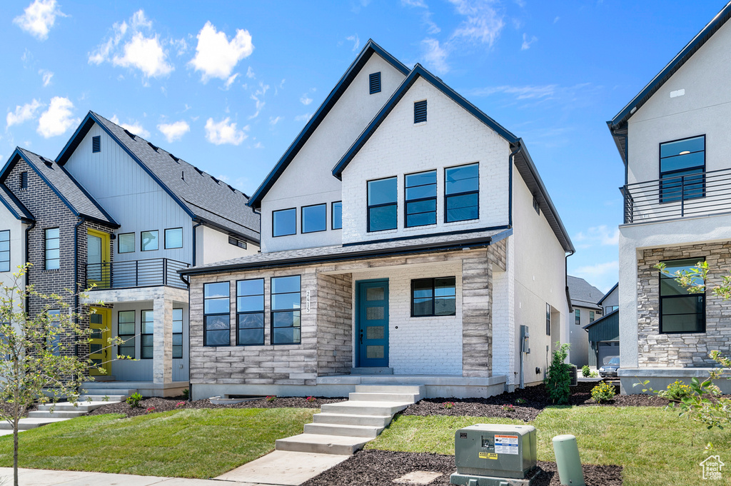 View of front of property featuring a front lawn, brick siding, and stone siding