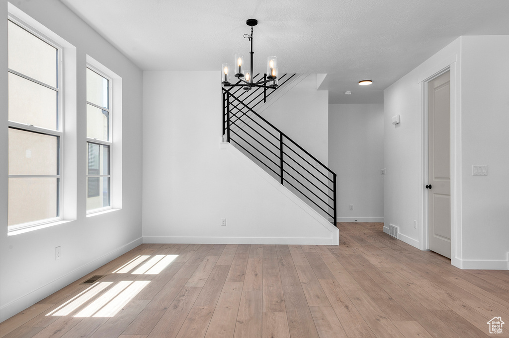 Interior space with a chandelier, stairs, light wood-type flooring, and baseboards
