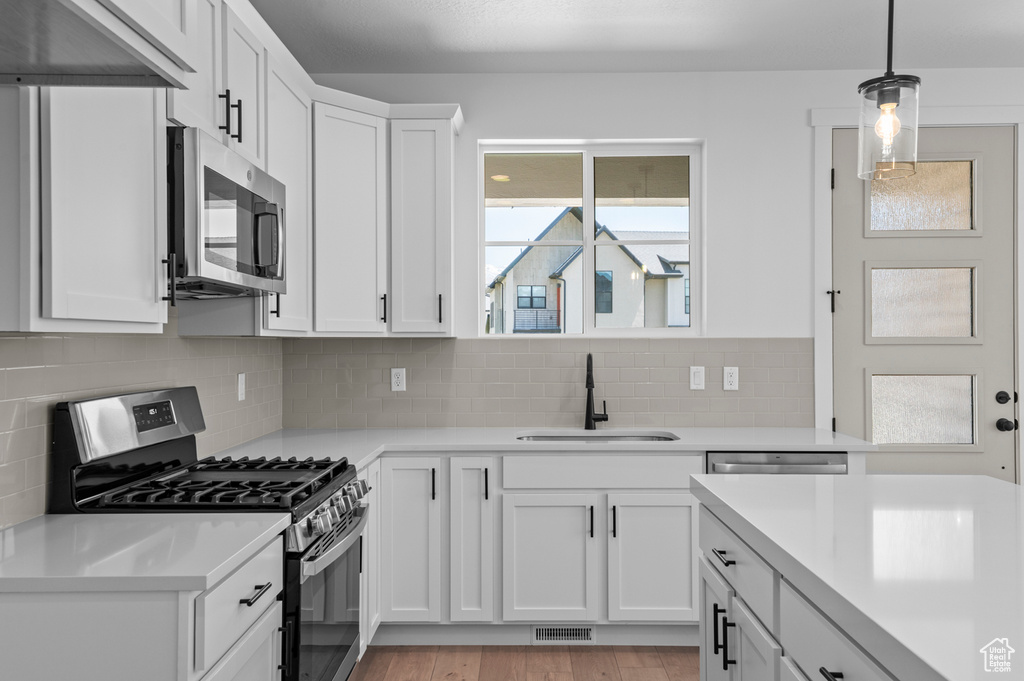 Kitchen with stainless steel appliances, a sink, light countertops, and white cabinets