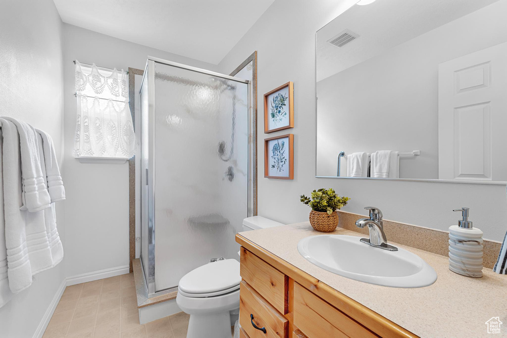 Full bath featuring a stall shower, vanity, toilet, and baseboards