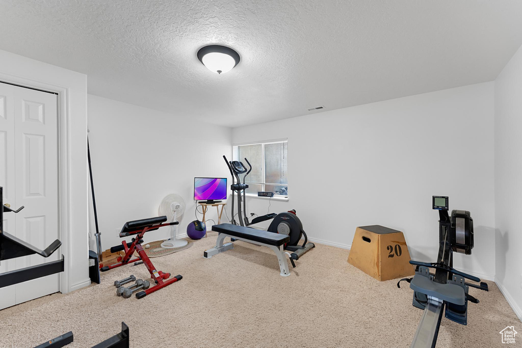 Exercise room featuring baseboards, a textured ceiling, and carpet