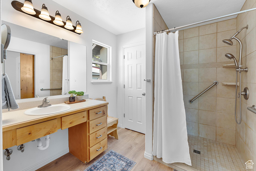Full bathroom with tiled shower, wood finished floors, and vanity