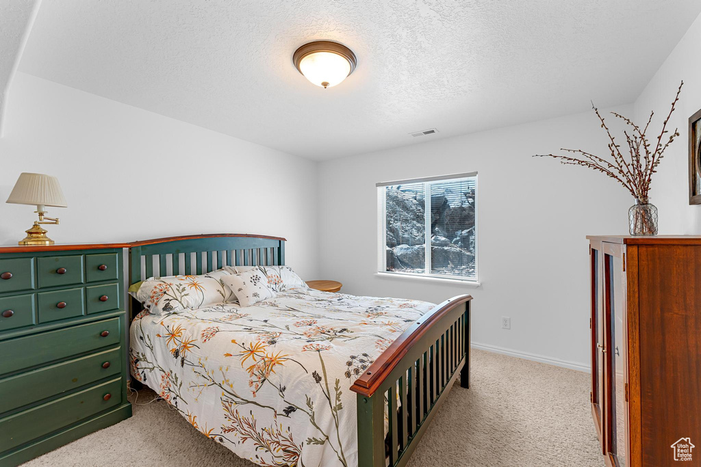 Carpeted bedroom featuring a textured ceiling and baseboards